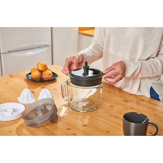 BLACKDECKER BXCJ30E citrus juicer parts on table, glass container, person assembling, kitchen setting