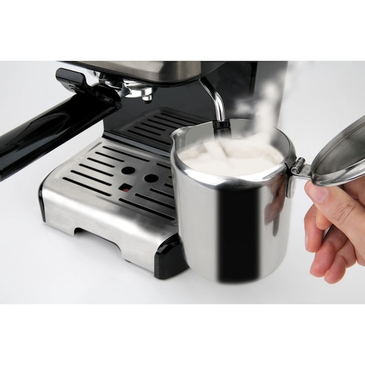 BLACKDECKER BXCO1200E espresso machine steaming milk in a stainless steel frothing jug, side angle.