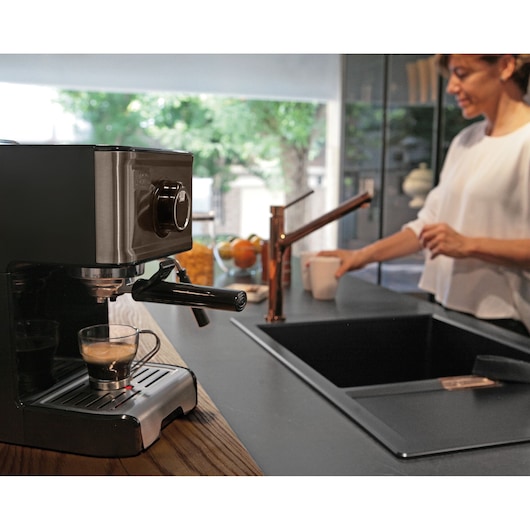 BLACKDECKER BXCO1200E coffee machine on kitchen counter with espresso cup, person in background.