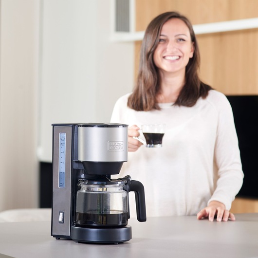 BLACKDECKER BXCO870E drip coffee maker in silver and black on kitchen counter, person holding a coffee cup.