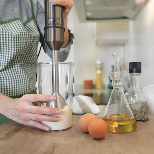 BLACKDECKER BXHB1000E hand blender used in kitchen beside eggs, oil, and spices.