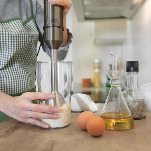 BLACKDECKER BXHBA1000E hand blender mixing ingredients in glass, eggs and oil on kitchen counter.
