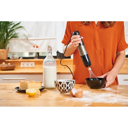 BLACKDECKER BXHBA1000E hand blender with whisk attachment in use on kitchen counter with baking ingredients.