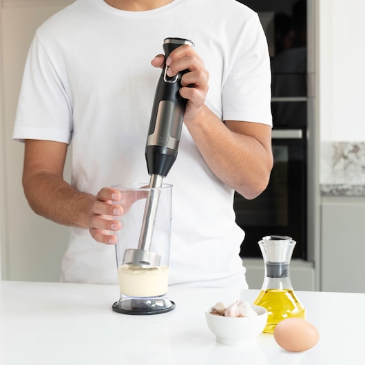 BLACKDECKER BXHBA1500E hand blender mixing ingredients in a clear container on kitchen counter.