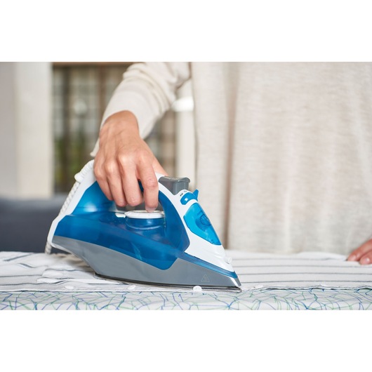 BLACKDECKER BXIR2200E steam iron with blue and white design in use on striped fabric.