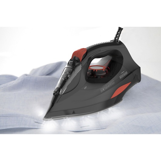 BLACKDECKER BXIR3000E steam iron with black and red design ironing a light blue shirt, side view.