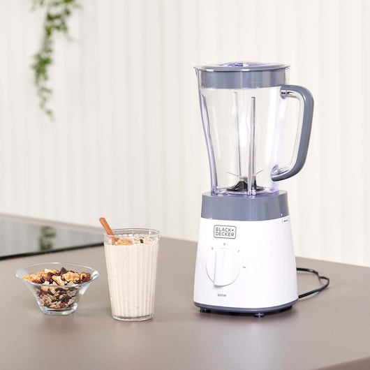 BLACK+DECKER BXJB500E blender, white and grey, side angle, next to smoothie and nuts on a kitchen counter.
