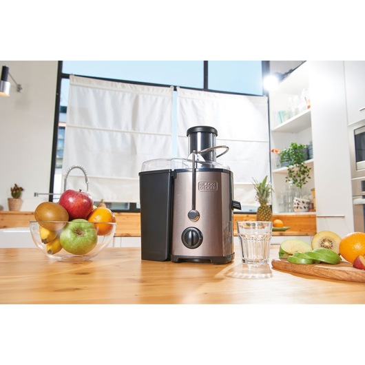 BLACKDECKER BXJE600E juicer on kitchen table with fruit bowl and sliced fruit, front angle.