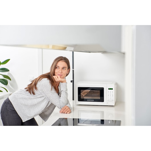 Photo of BLACKDECKER BXMZ701E white microwave oven on kitchen counter with digital control panel.