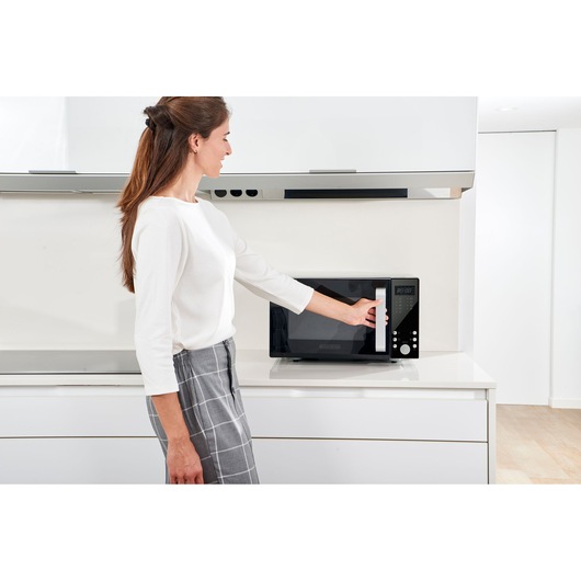 Photo of a person opening a BLACK+DECKER BXMZ900E microwave oven on a kitchen counter.