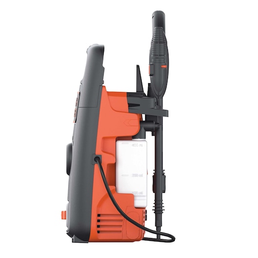 Side view of a BLACK+DECKER pressure washer, model BXPW1300E, in orange and black, showing the attached spray gun and hose, with a visible detergent bottle slot.