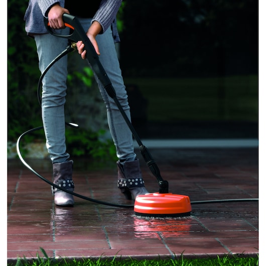 BLACKDECKER BXPW1700PE pressure washer cleaning wet outdoor tiles, close-up, person holding handle.