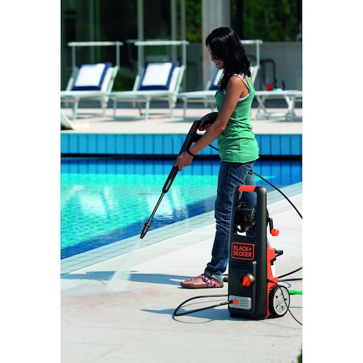 BLACK+DECKER BXPW1800PE pressure washer cleaning poolside, person using spray wand outdoors.