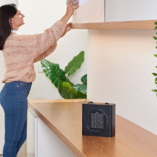 BLACKDECKER BXSH1500E black portable heater on wooden surface in modern indoor setting.