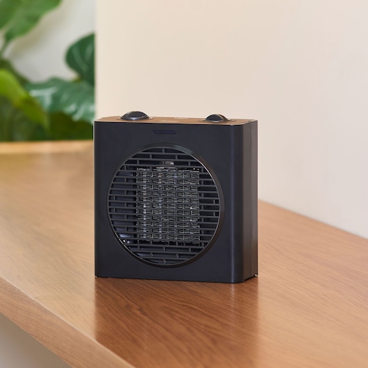 BLACKDECKER BXSH1500E black compact space heater on wooden surface, front angle.