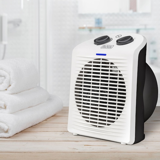 BLACKDECKER BXSH2000E white and black portable fan heater on wooden surface near towels.