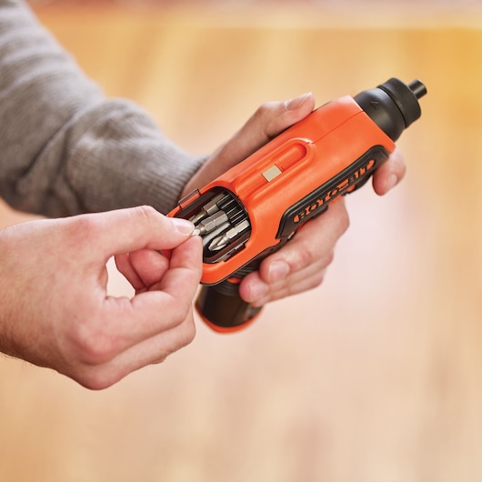 BLACK+DECKER CS36BSCES orange cordless screwdriver with built-in bit storage held in hand, bit being selected.