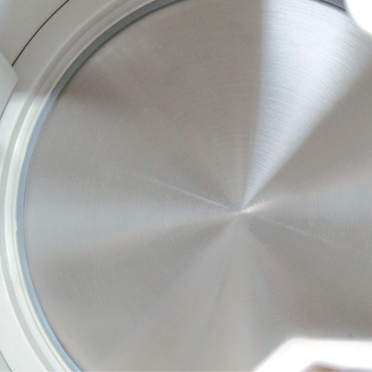 Close-up view of a metallic circular surface with a brushed texture, surrounded by a white rim.