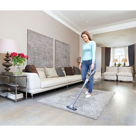 Photo of BLACKDECKER DVA315JF stick vacuum cleaner used on a grey rug in a modern living room.