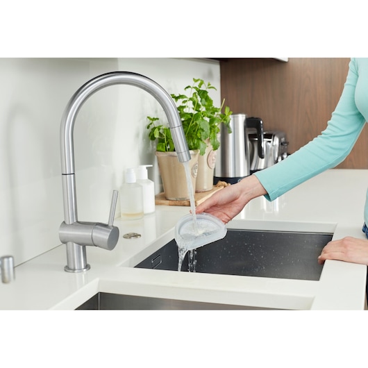 BLACKDECKER DVA315JF handheld vacuum filter being rinsed under kitchen faucet, top view.