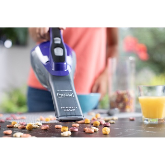BLACKDECKER DVA325JP07 handheld vacuum cleaning cereal from a table, close-up photography.