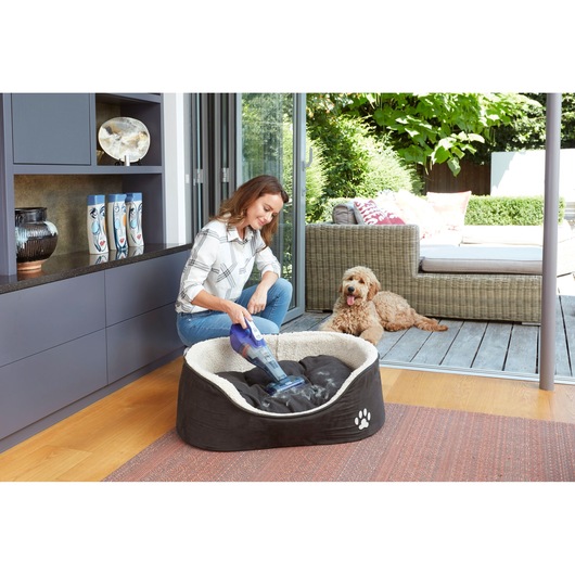 BLACKDECKER DVB315JP handheld vacuum used to clean dog bed indoors, with dog resting nearby.