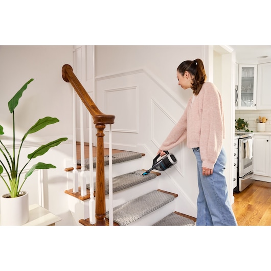 BLACKDECKER DVD320B handheld vacuum cleaning carpeted stairs in home setting.