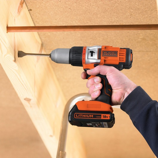 BLACKDECKER EGBHP1881BK cordless drill being used to drill into wood, close-up with battery visible.