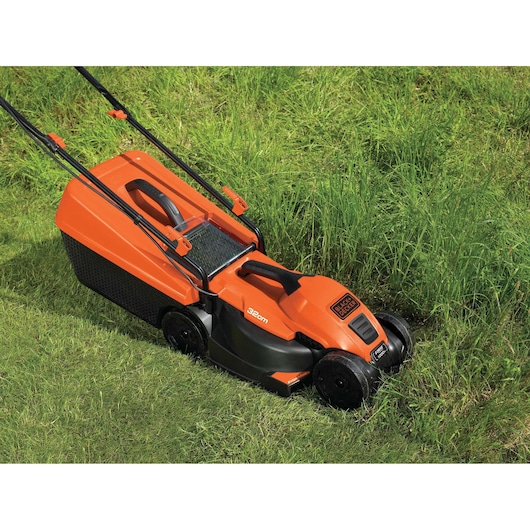 BLACKDECKER EMAX32S orange lawn mower on grass, side angle, compact design, prominent handle and wheels.