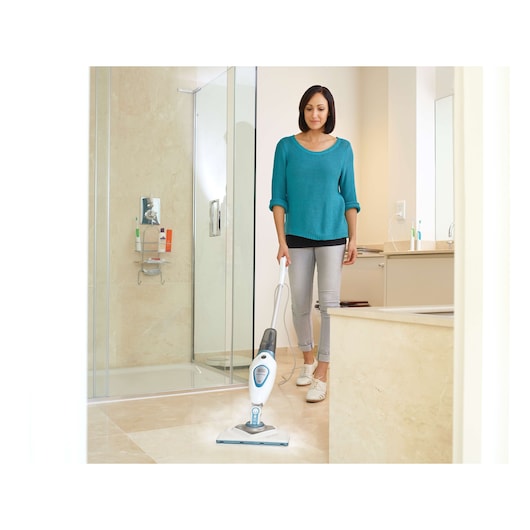 BLACKDECKER FSM1616 steam mop cleaning bathroom floor, held by person in casual clothes.