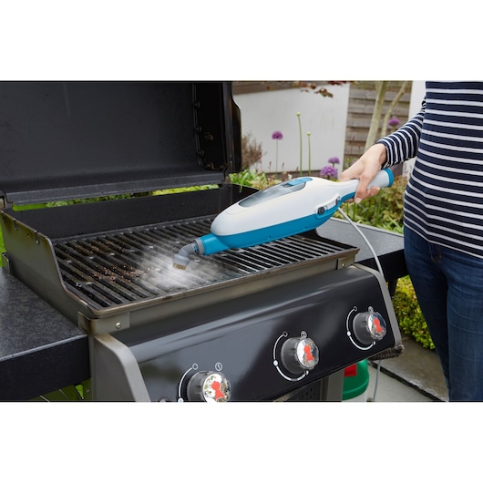 BLACKDECKER FSMH13E5 steam cleaner cleaning barbecue grill, side angle outdoors.