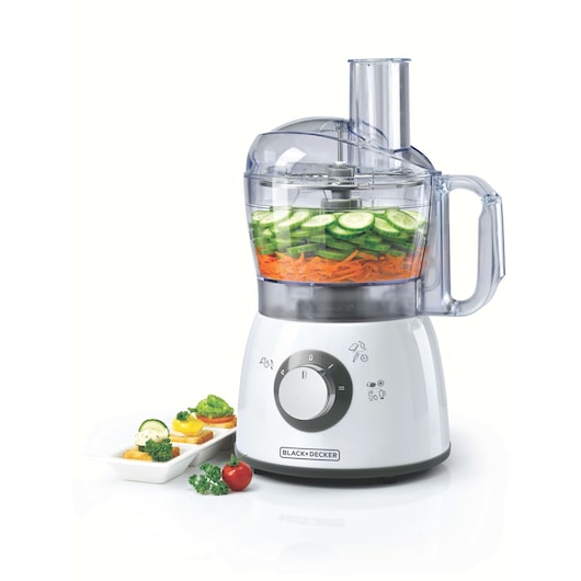 A BLACK+DECKER food processor model FX400 with a transparent bowl containing sliced cucumbers and grated carrots. The appliance has a control dial on the front and a side handle. Next to it is a white plate with sliced vegetables and herbs.