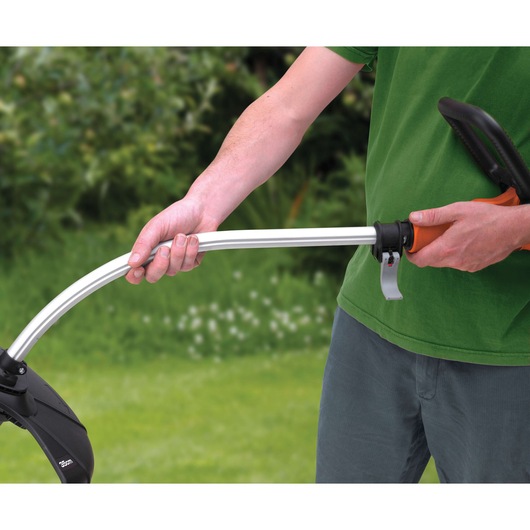 BLACKDECKER GL7033CAKIT grass trimmer held by person in green shirt, garden background, close-up view