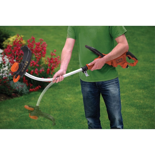 BLACKDECKER GL8033 grass trimmer in use, orange and black design, held by a person in a garden.