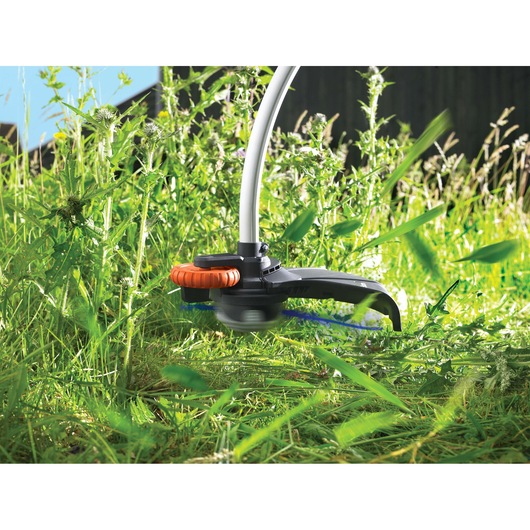 BLACKDECKER GL933 grass trimmer head in action cutting tall green grass outdoors.