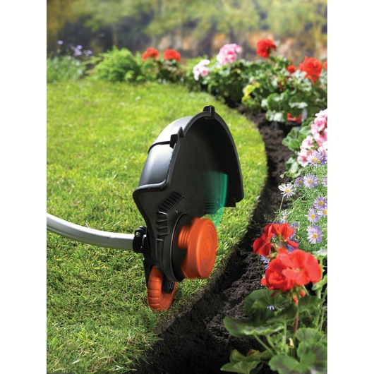 BLACKDECKER GL933 lawn trimmer in use edging grass border near colorful flowers.