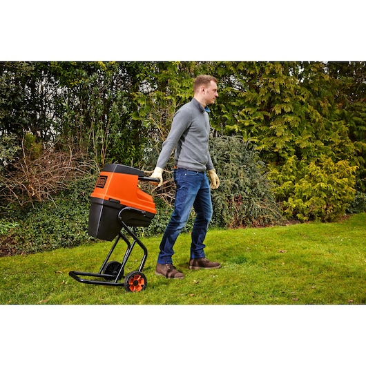 Photo of BLACKDECKER GS2400 garden shredder with orange and black body, being pulled by a person outdoors.