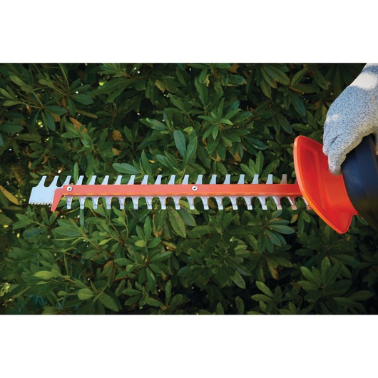 BLACKDECKER hedge trimmer blade GTC5455PC in use, close-up, cutting green hedge.