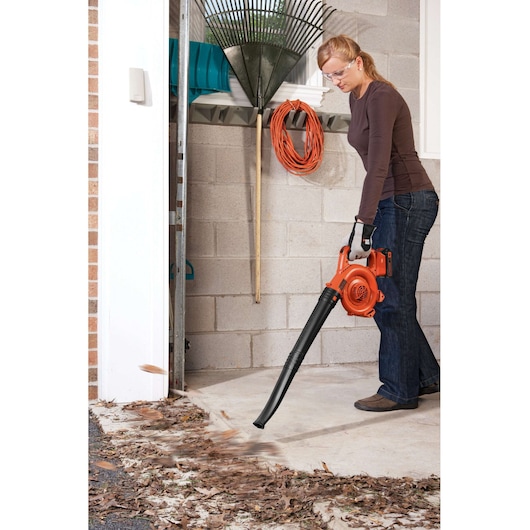 BLACKDECKER GWC1800L20 leaf blower in use indoors, orange and black design, person clearing leaves.
