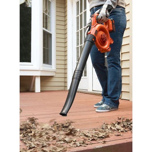 BLACKDECKER GWC1800L20 cordless leaf blower in use clearing leaves from a wooden deck, close-up view.