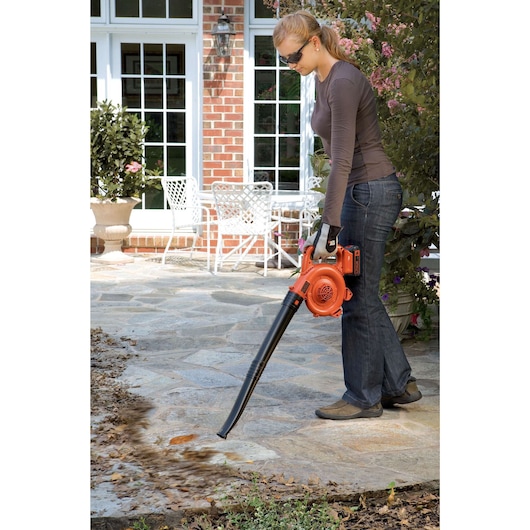 Photo of BLACKDECKER GWC1800L20 cordless leaf blower in use on patio, orange and black design.