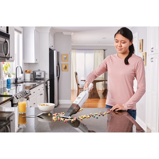 Photo of BLACKDECKER HLVC315B11 handheld vacuum cleaning cereal from a kitchen counter.