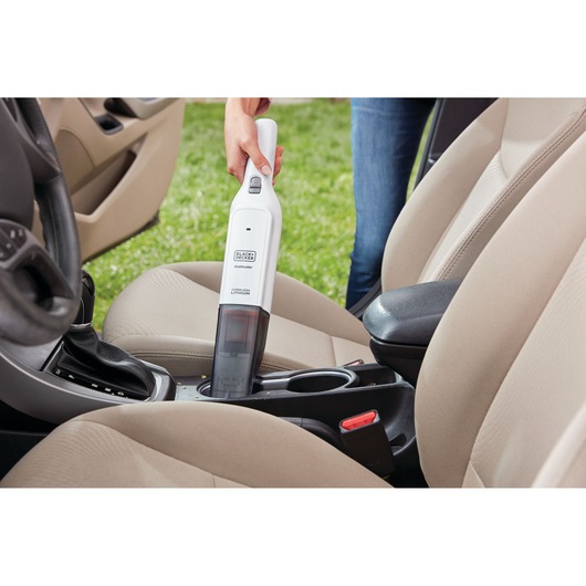 Photo of BLACKDECKER HLVC315B11 cordless handheld vacuum cleaning a car’s interior between front seats.