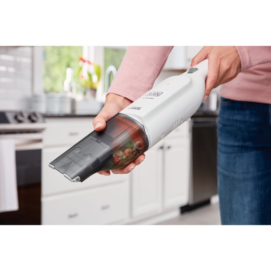 BLACKDECKER HLVC315B11 handheld vacuum in use cleaning crumbs in a kitchen.