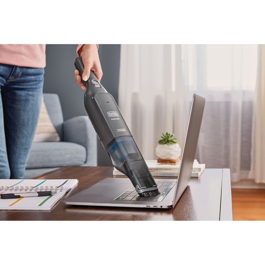 BLACK+DECKER HLVC320B11 cordless handheld vacuum cleaning laptop keyboard on desk.