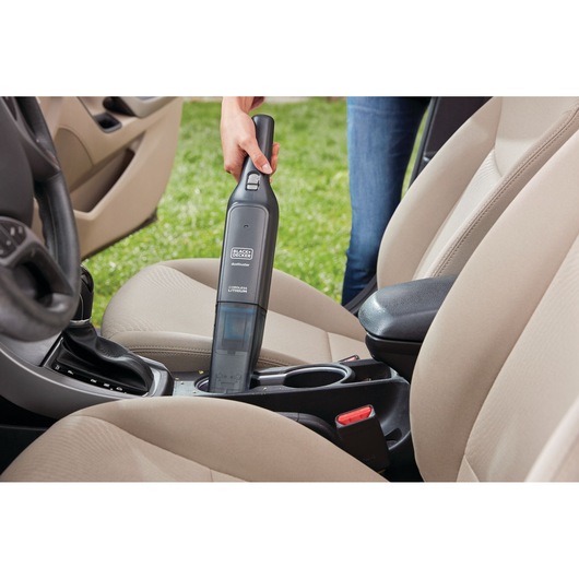 BLACK+DECKER HLVC320B11 handheld vacuum cleaning beige car interior cup holder area.