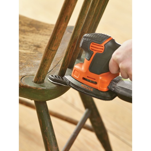 BLACKDECKER KA2500K sander in use refinishing an old wooden chair, close-up view.