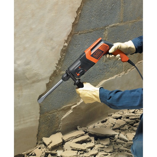 BLACKDECKER KD885KC rotary hammer used for wall demolition, close-up with gloved hands, rubble visible.