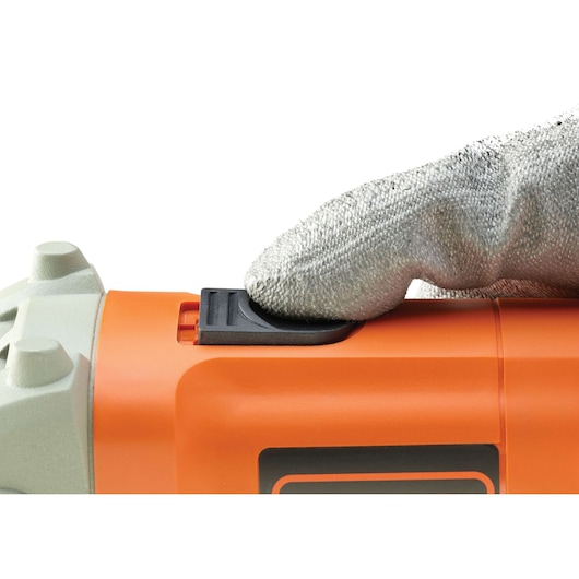 Photo of BLACKDECKER KG115 angle grinder power switch being operated by a gloved hand, close-up side view.