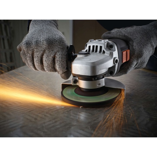 BLACKDECKER KG911K angle grinder in use, producing sparks while grinding metal, close-up view of hands wearing gloves.